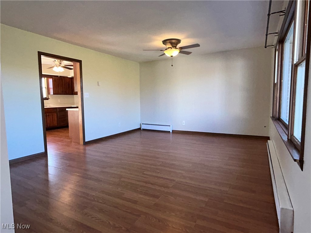 56376 Jordan Run Road Bellaire, OH 43906 - Photo 11 of 45 Empty room featuring baseboards, a baseboard radiator, a ceiling fan, and dark wood finished floors