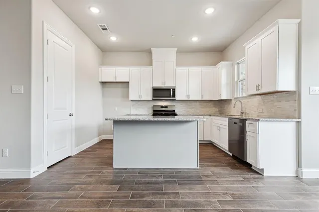 a kitchen with granite countertop a stove top oven and white cabinets