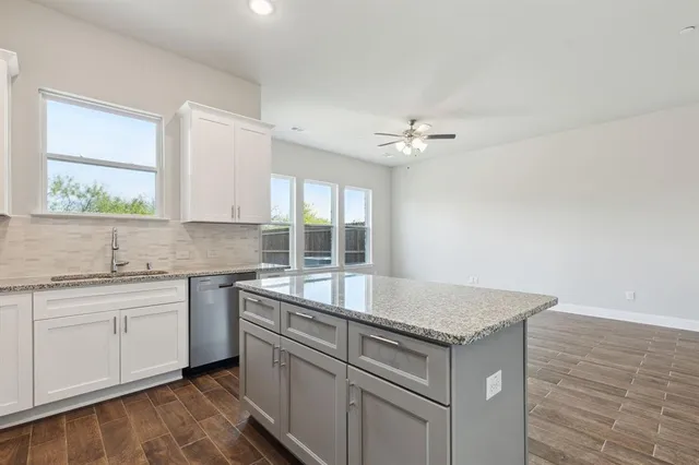 a kitchen with granite countertop a sink stove and cabinets