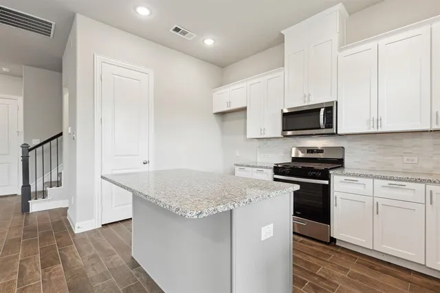 a kitchen with stainless steel appliances granite countertop a stove a sink and a microwave
