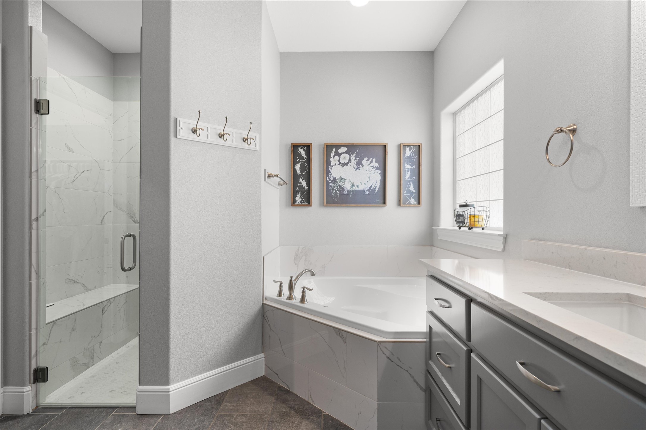 136 Fawn Hollow Elgin, TX 78621 - Photo 18 of 40 Spacious bathroom featuring a glass-enclosed shower with a built-in bench, a corner soaking tub with deck-mounted fixtures, and a vanity with an undermount sink and stone-finish countertop