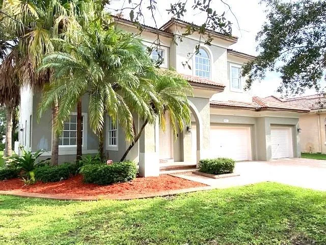 a front view of a house with a yard and palm trees
