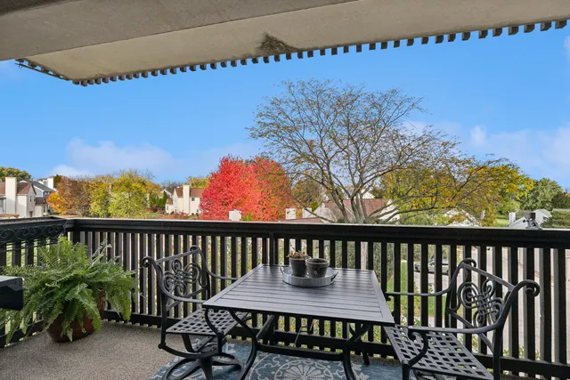 a view of a balcony with chairs and wooden fence