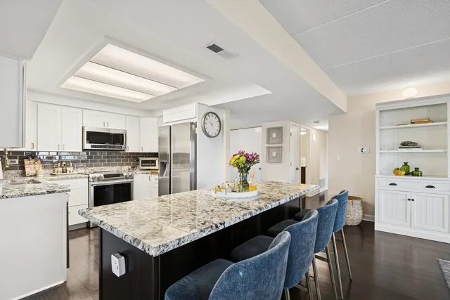 a kitchen with granite countertop kitchen island wooden cabinets and stainless steel appliances