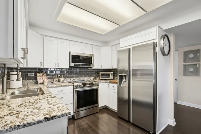a kitchen with stainless steel appliances granite countertop a refrigerator a stove and a sink