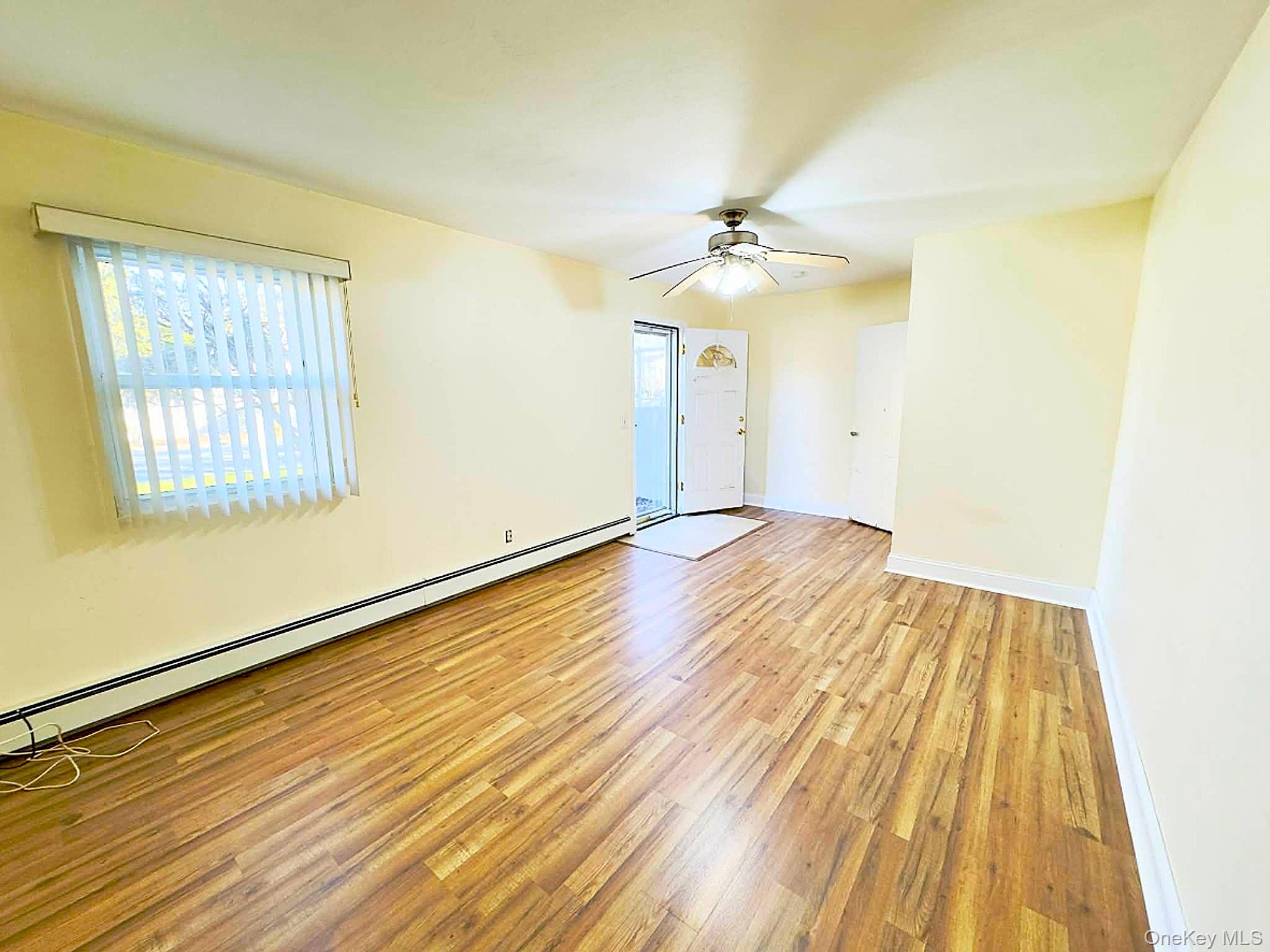 308 Browns Road Nesconset, NY 11767 - Photo 21 of 34 an empty room with wooden floor chandelier fan and windows