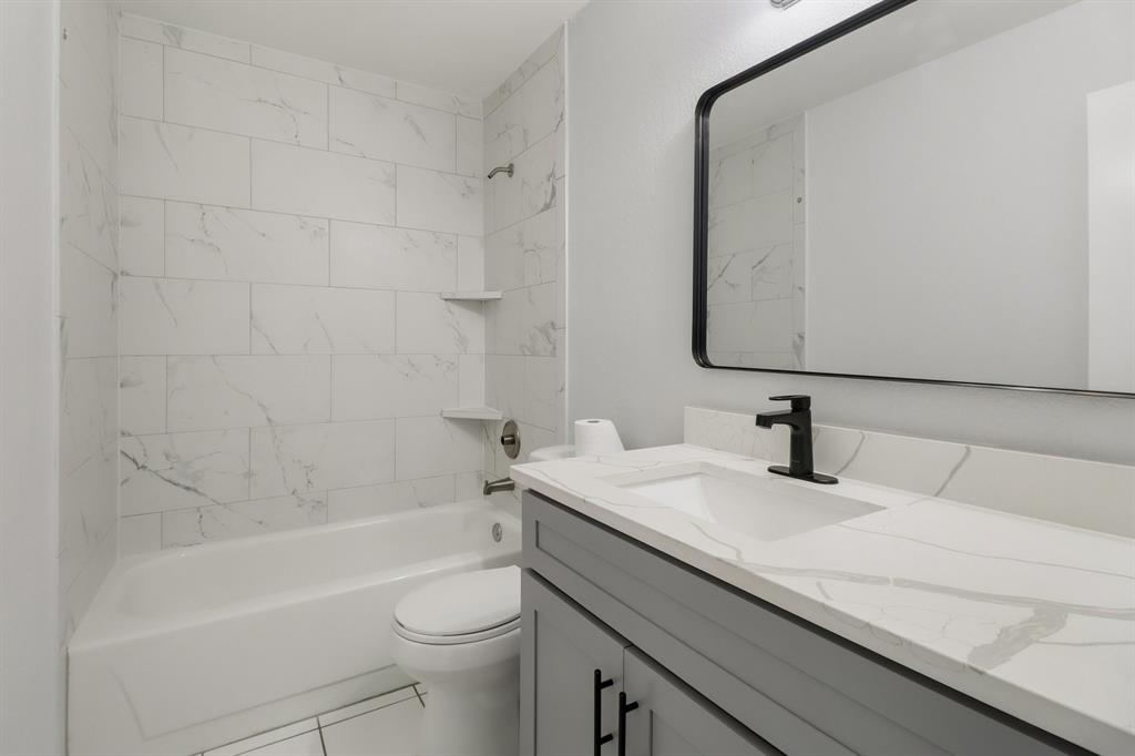 413 Chimney Rock Road Everman, TX 76140 - Photo 21 of 25 a bathroom with a granite countertop sink a toilet and bathtub