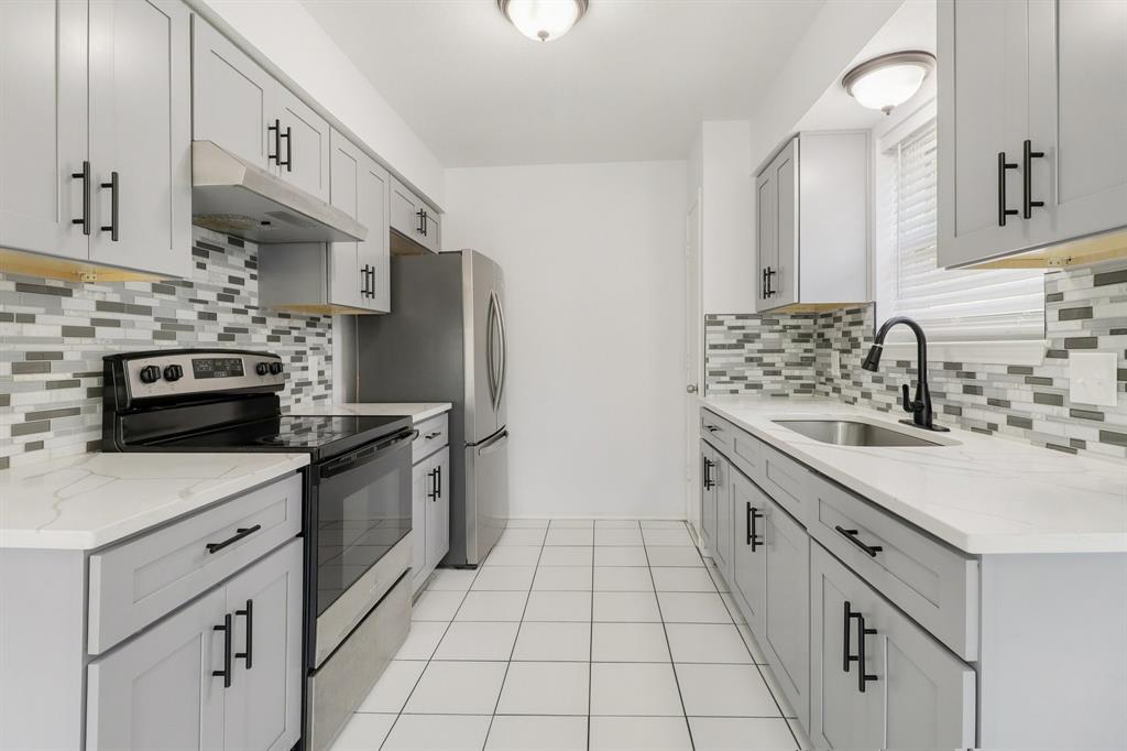 413 Chimney Rock Road Everman, TX 76140 - Photo 3 of 25 a kitchen with stainless steel appliances a sink stove and cabinets