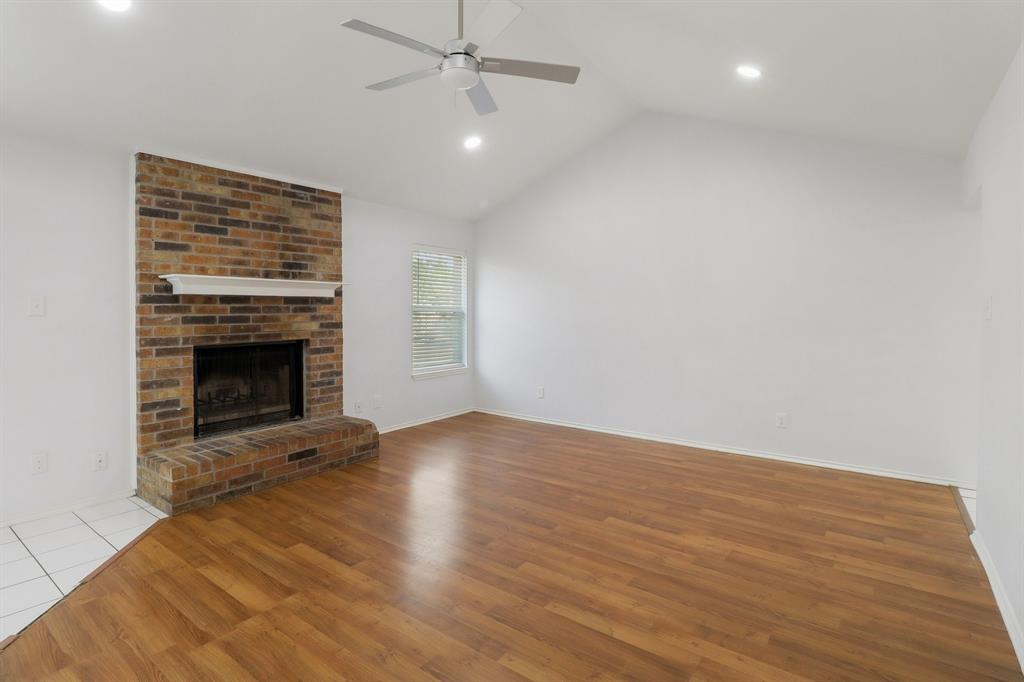 413 Chimney Rock Road Everman, TX 76140 - Photo 4 of 25 an empty room with wooden floor fireplace and a window