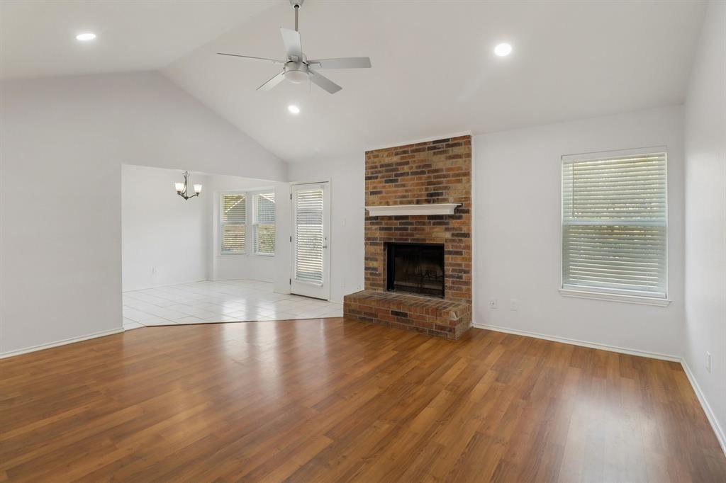 413 Chimney Rock Road Everman, TX 76140 - Photo 8 of 25 an empty room with wooden floor fireplace and windows
