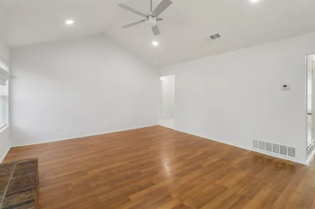 an empty room with wooden floor and fan
