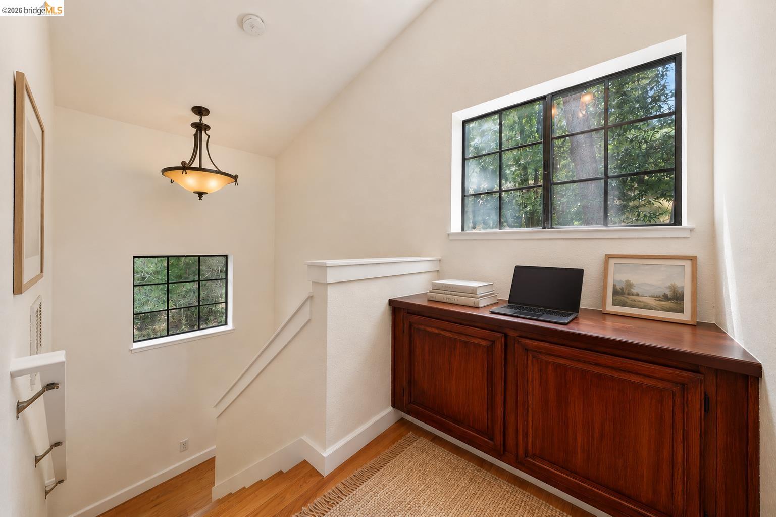 261 Redhawk Road Novato, CA 94949 - Photo 24 of 44 Upper landing featuring a built-in wood-finish cabinet with panel doors, a large transom window with black muntins, a smaller rectangular window, and a ceiling-mounted light fixture