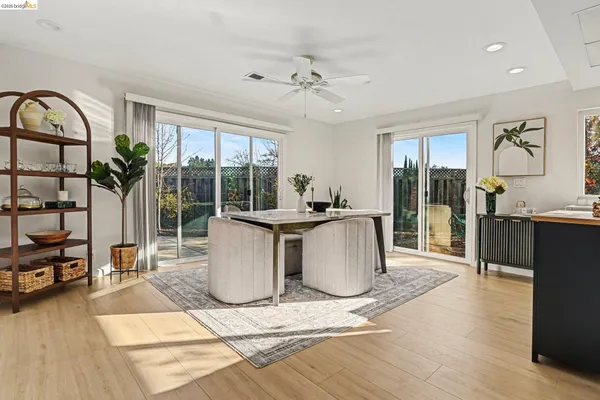 a living room with a large window and a dining table with garden view