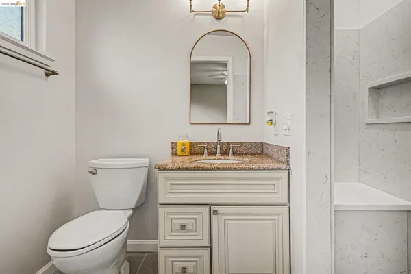 a bathroom with a granite countertop toilet sink and mirror