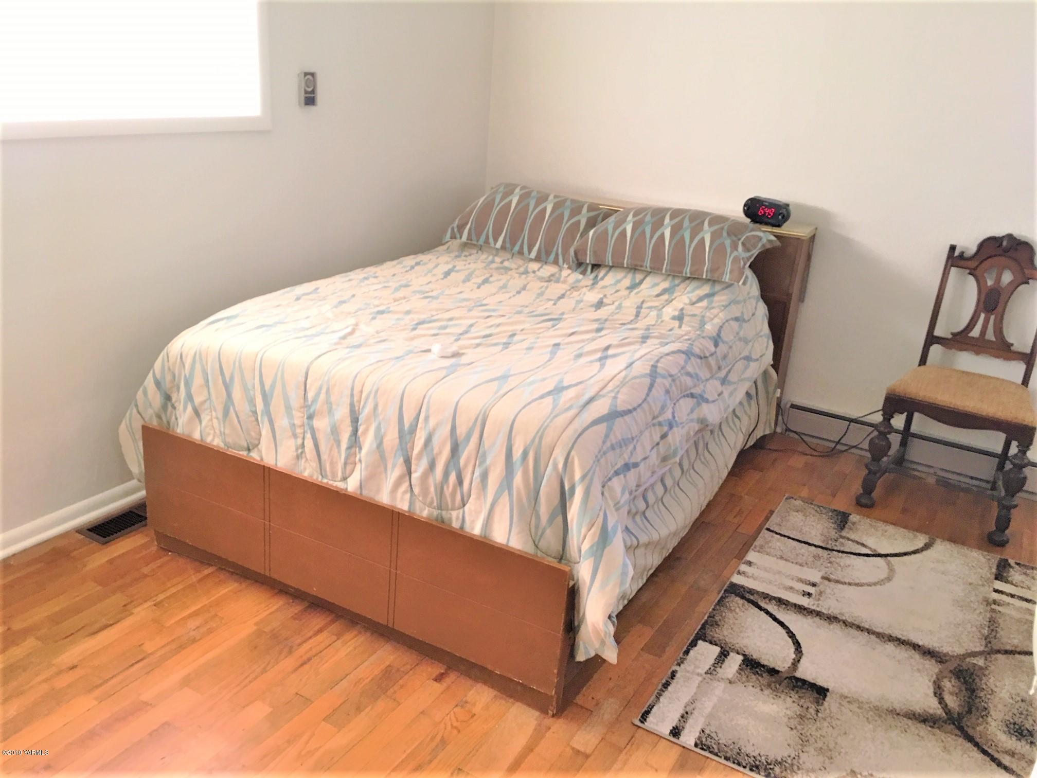1220 Swan Road Sunnyside, WA 98944 - Photo 9 of 22 a bed sitting in a bedroom next to a window with chair