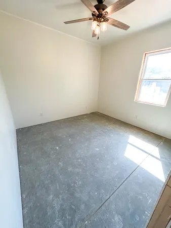 an empty room with a ceiling fan and a window