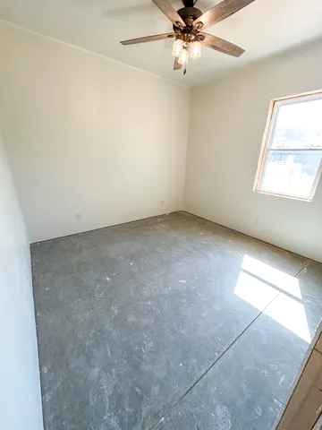 an empty room with a ceiling fan and a window