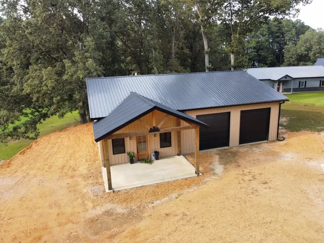 a view of a house with large trees and wooden fence
