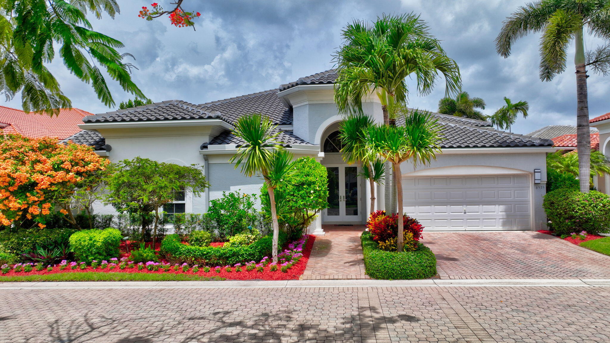 6535 Somerset Circle Boca Raton, FL 33496 - Photo 56 of 59 a front view of yellow house with a yard and a garage
