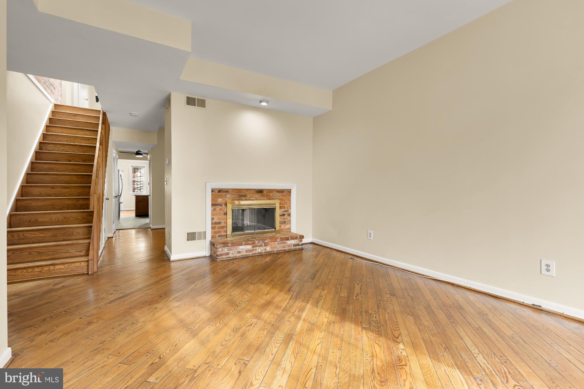 a view of an empty room with wooden floor and a fireplace