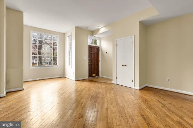 a view of an empty room with wooden floor and windows