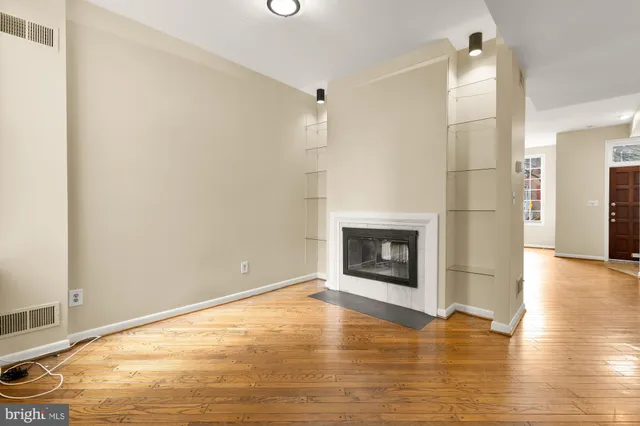 a view of empty room with wooden floor and fireplace