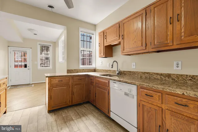 a kitchen with granite countertop wooden cabinets a sink and dishwasher