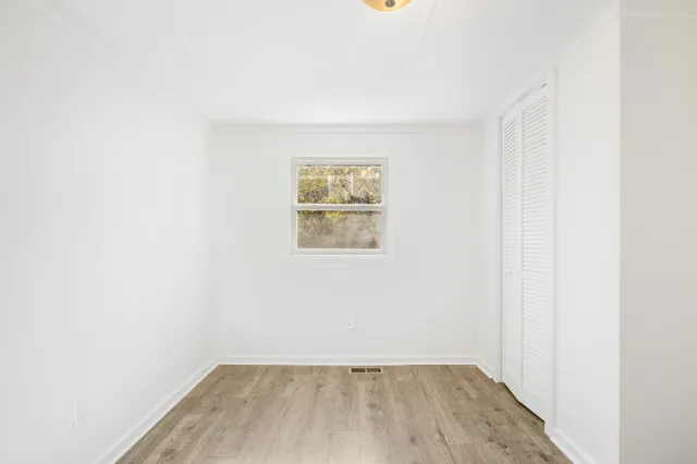 an empty room with wooden floor and window