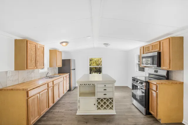 a open kitchen with stainless steel appliances granite countertop a stove top oven a sink a counter space and cabinets