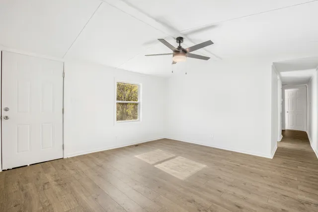 an empty room with wooden floor closet and fan