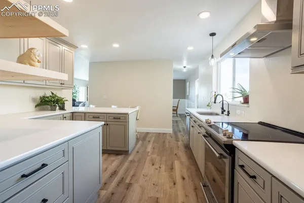 a kitchen with a sink stove cabinets and wooden floor