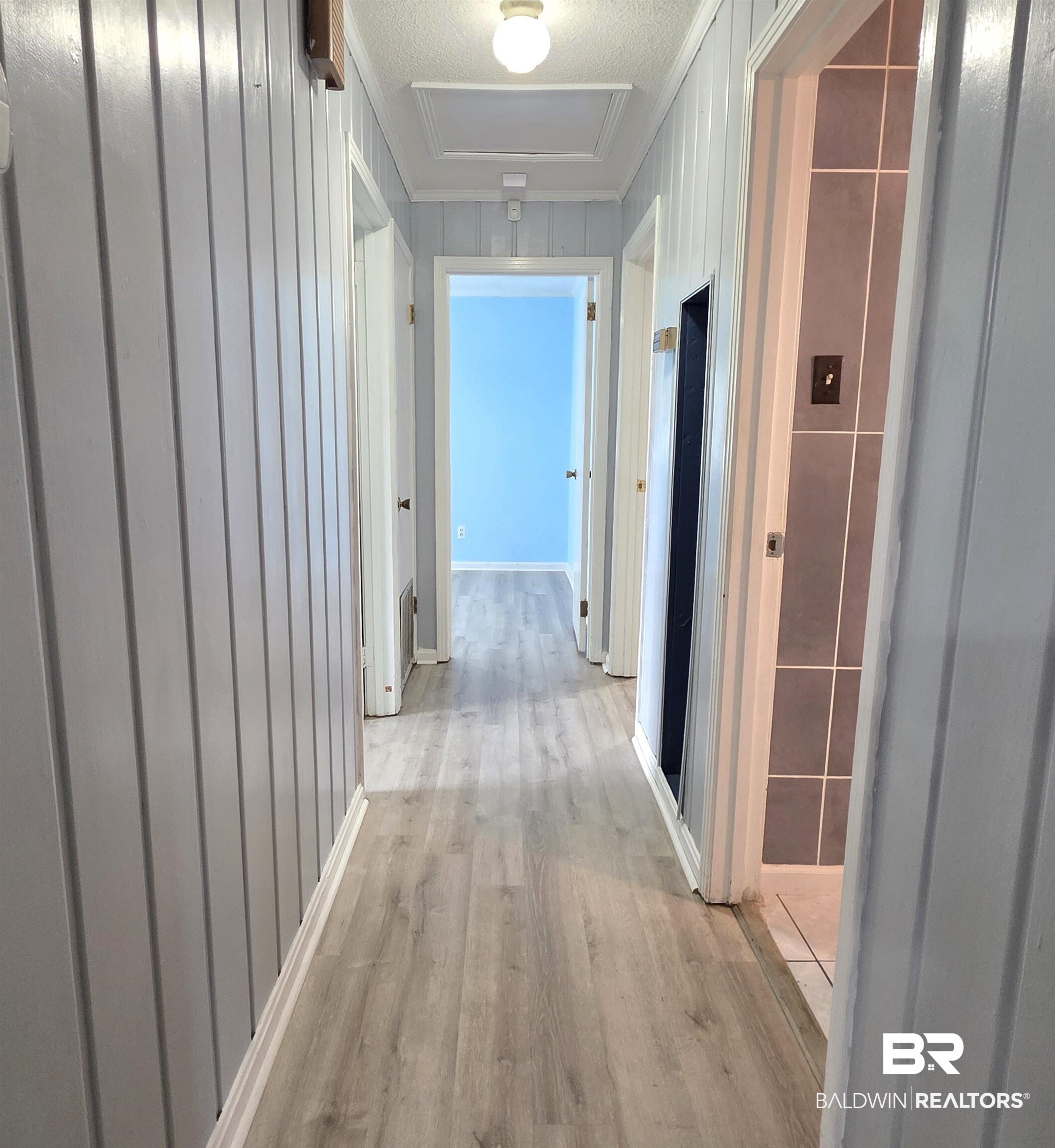 558 Stanton Road Atmore, AL 36502 - Photo 13 of 29 Hallway featuring wood-finish flooring, vertical paneling, and multiple doorways
