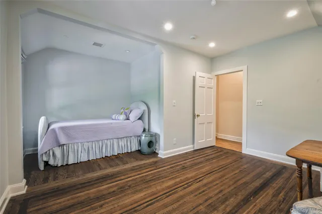 a spacious bedroom with a bed and wooden floor