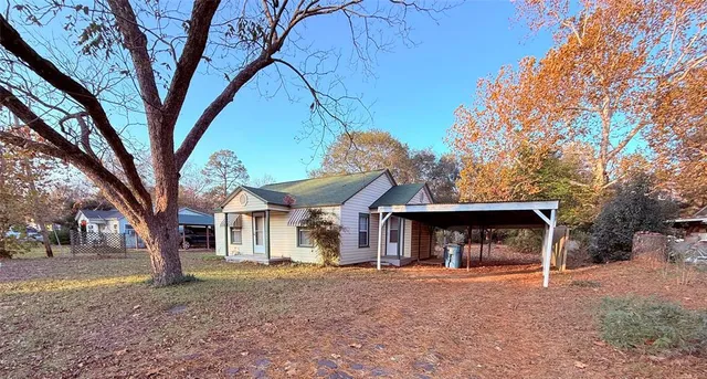 a view of a house with a yard and large tree