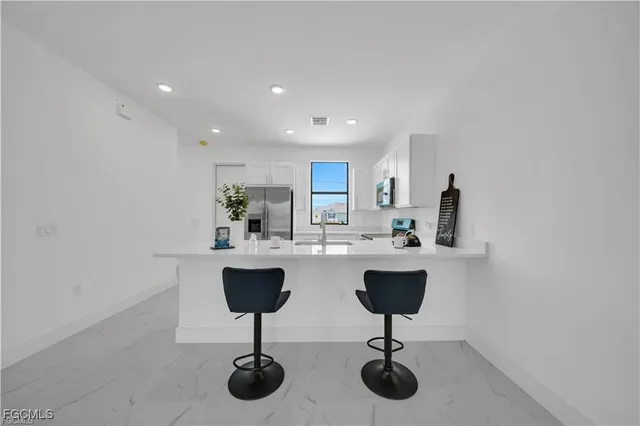 a kitchen with stainless steel appliances kitchen island granite countertop a refrigerator a stove and a sink with wooden floor