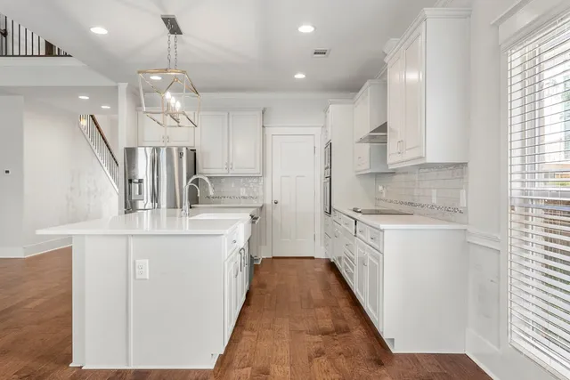 a kitchen with kitchen island granite countertop a sink a counter space appliances and cabinets