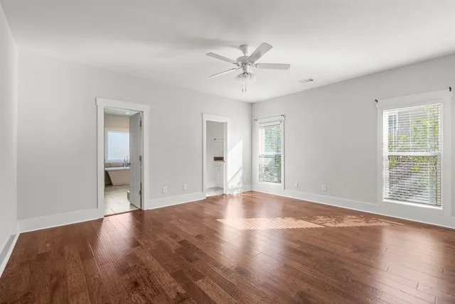 a view of an empty room with window and wooden floor