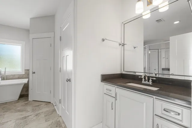 a bathroom with a granite countertop sink a large mirror and a bathtub