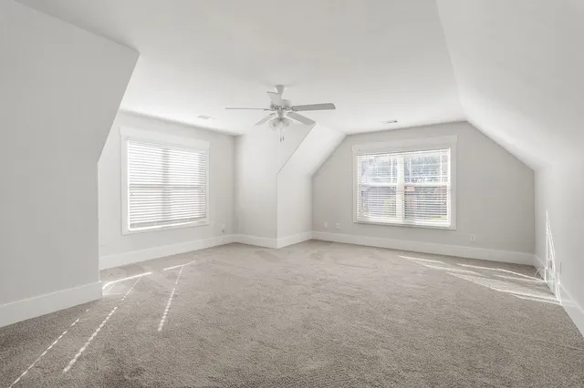 an empty room with windows and ceiling fan