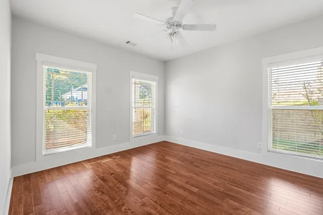 a view of an empty room with wooden floor and a window