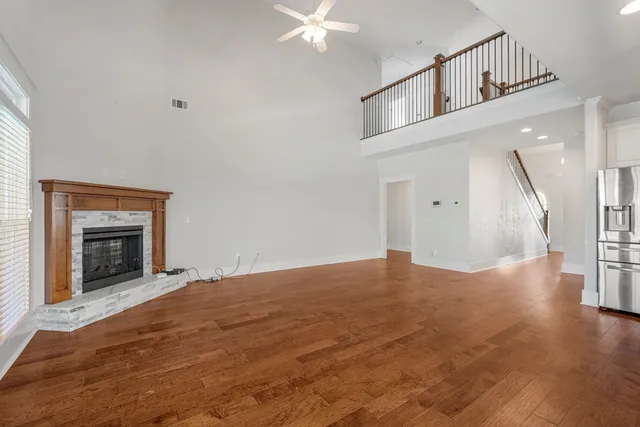 a view of an empty room with wooden floor fireplace and a window