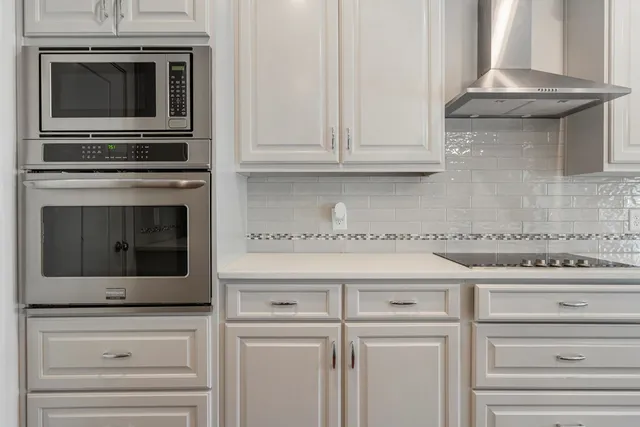 a kitchen with granite countertop white cabinets stainless steel appliances and a fireplace