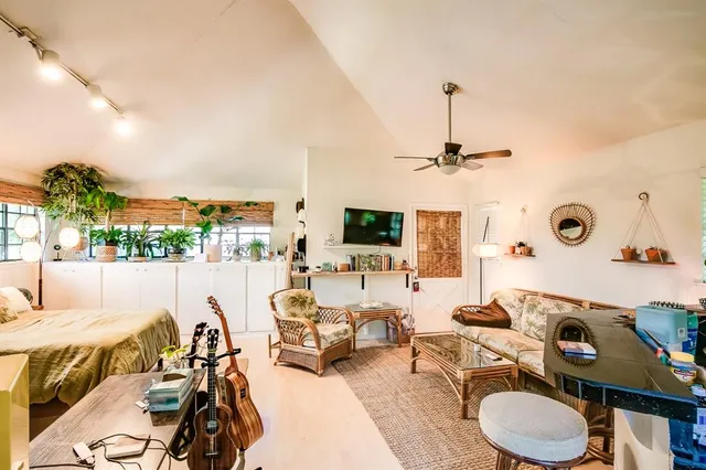 a living room with furniture a flat screen tv and a floor to ceiling window