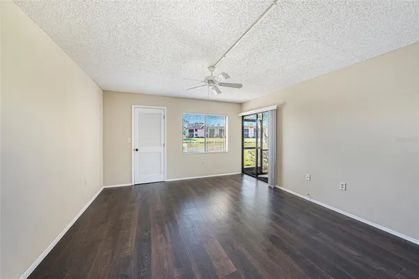 a view of an empty room with window and wooden floor