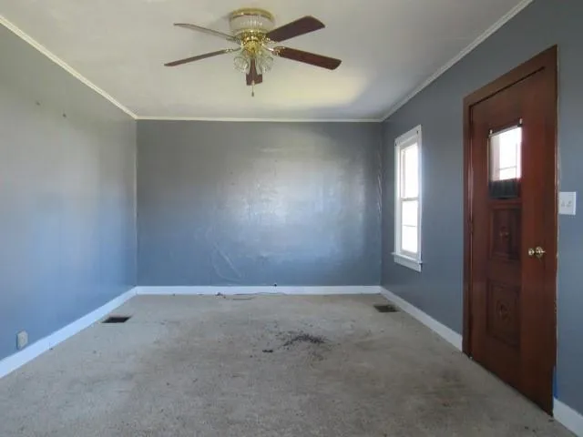 an empty room with a chandelier fan and windows