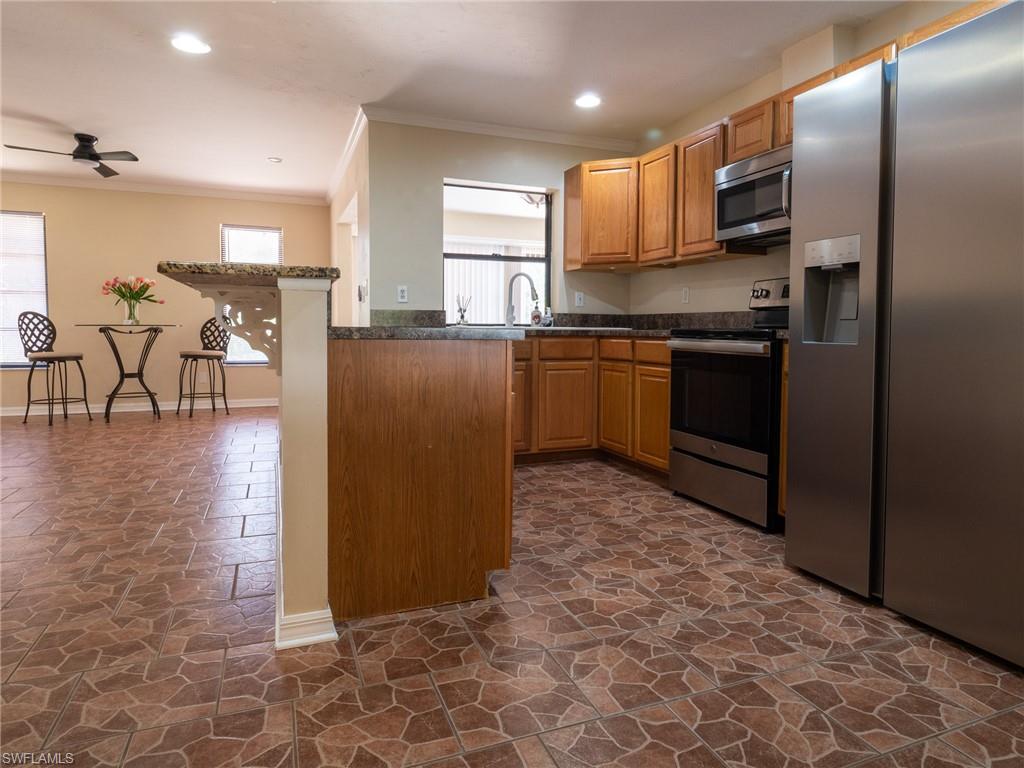 18414 Tulip Road Fort Myers, FL 33967 - Photo 7 of 37 Kitchen featuring wood cabinetry, stainless steel appliances, dark countertops, and patterned tile flooring