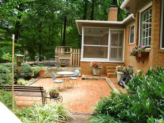 6808 Breezewood Road Raleigh, NC 27607 - Photo 3 of 12 Brick patio, lower deck with seating and upper deck overlooking yard. French door from master bedroom allows access to deck and view of private yard and natural habitat beyond.