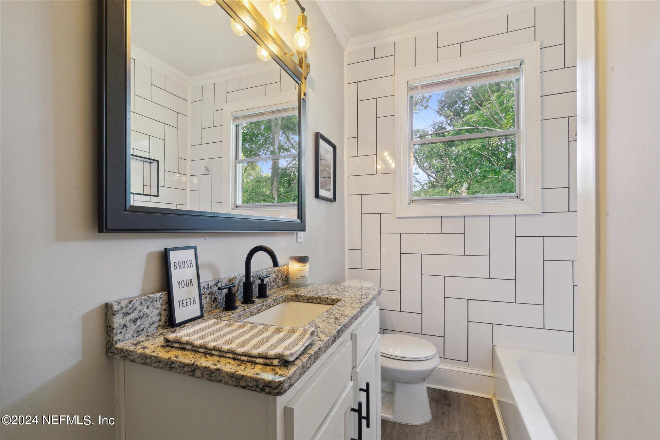 1262 Murray Drive Jacksonville, FL 32205 - Photo 27 of 42 a bathroom with a granite countertop toilet a sink and a mirror