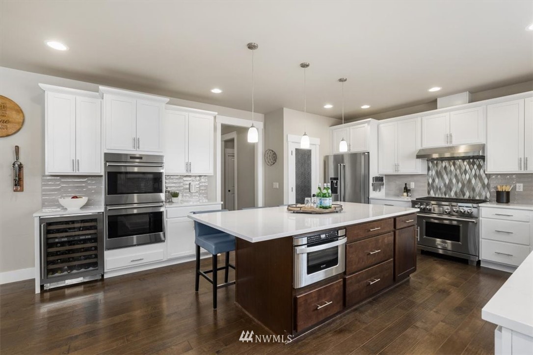 1441 242nd Place Southeast Bothell, WA 98021 - Photo 7 of 40 a kitchen with kitchen island granite countertop a stove cabinets and wooden floor