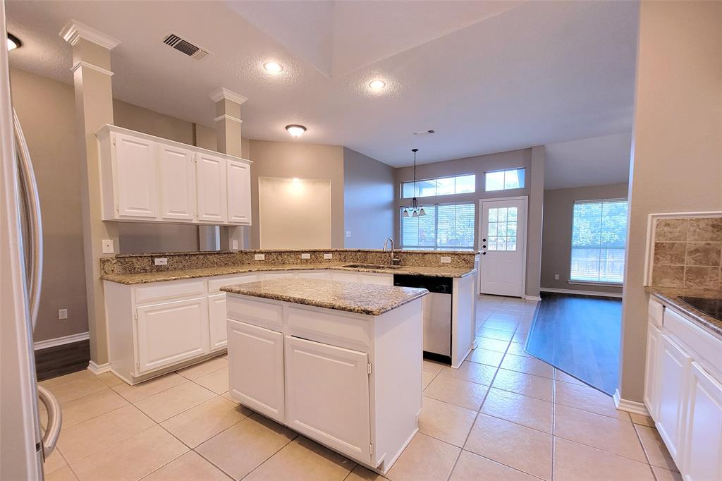 1604 Knoll Ridge Circle Corinth, TX 76210 - Photo 12 of 37 Kitchen featuring white cabinetry, granite countertops, a central island, stainless steel dishwasher, and tile flooring